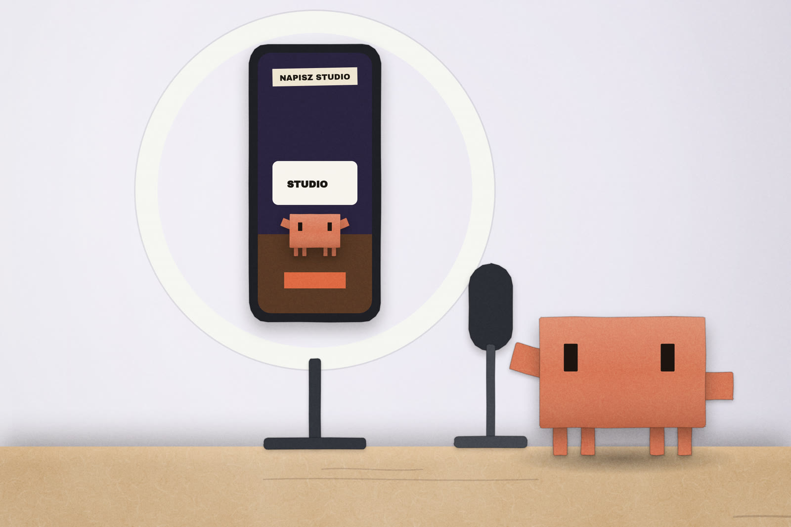 Telefon na statywie z lampą pierścieniową odtwarza reels z planszą NAPISZ STUDIO, obok mikrofon i Clawd